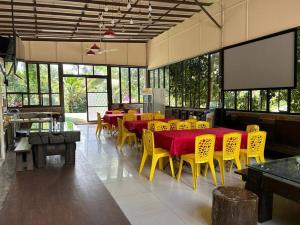un restaurant avec des tables, des chaises jaunes et un écran dans l'établissement Bentong Nature Orchard Homestay, à Bentong