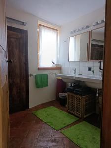 a bathroom with two sinks and a green rug at La Capinera in Muggio