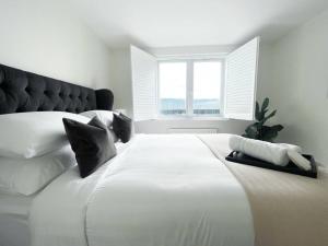 a large white bed in a bedroom with a window at Stunning modern space with harbour views & free parking in Brighton & Hove