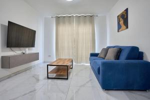 a living room with a blue couch and a table at The Hill 245 Modern Apt: 10 Minutes from the Beach in Taʼ Ċikkun