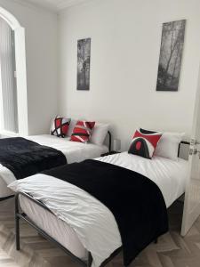 two beds in a room with white walls at Moorside House in Bolton