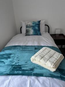 a blanket on a bed with a towel on it at Moorside House in Bolton