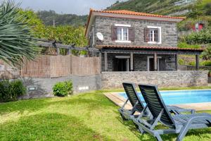 a villa with a swimming pool and two lawn chairs at Casa do Pombal, a Home in Madeira in Arco da Calheta