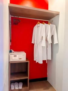 un armario con camisas blancas y una pared roja en Meir Jarr Hotel Patong en Patong
