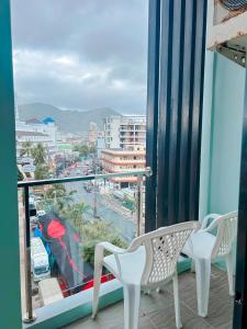 balcón con sillas y vistas a la ciudad en Meir Jarr Hotel Patong en Patong