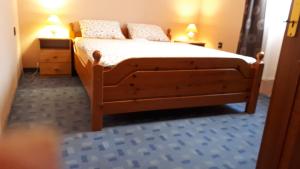 1 dormitorio con 1 cama de madera y 2 mesitas de noche en Magdaléna Panzio en Esztergom
