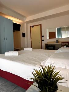 una camera con due grandi letti e due piante di Hotel Grecale - Venturina Terme a Venturina Terme