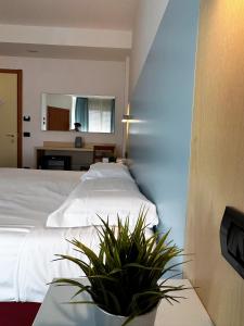 Un dormitorio con una cama blanca y una mesa con una planta en Hotel Grecale - Venturina Terme, en Venturina Terme