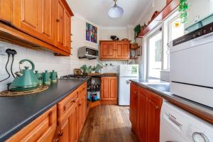 een keuken met houten kasten en een groene waterkoker op het aanrecht bij Charming Terraced 3BR House, 5 min Hither Green St in Londen