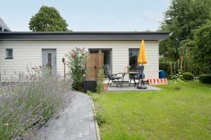 a small white shed with a table and a yellow umbrella at Haus Alouette in Dahme