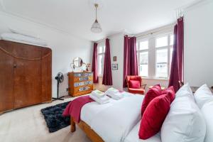 een slaapkamer met een bed met rode en witte kussens bij Charming Terraced 3BR House, 5 min Hither Green St in Londen