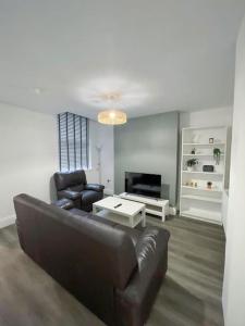 a living room with a leather couch and a tv at Newly refurbished 3 bed house in Hull