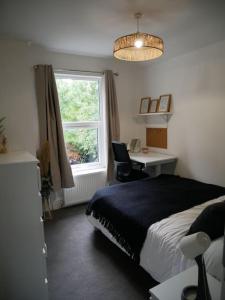 een slaapkamer met een bed, een bureau en een raam bij Newly refurbished 3 bed house in Hull