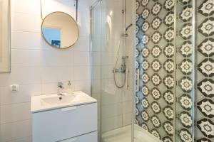 een badkamer met een douche, een wastafel en een spiegel bij Tomte - scandinavian apartment in Krakau