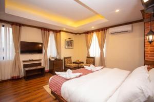1 dormitorio con 1 cama blanca grande y TV en Pashupati Boutique Hotel & Spa, en Katmandú