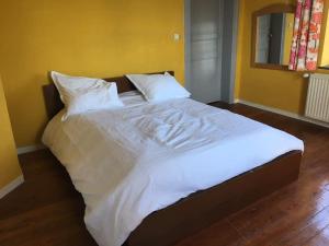 een groot bed met witte lakens en kussens in een kamer bij La Casa Kemtio in Nollevaux