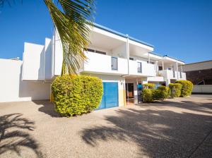 a white building with a palm tree in front of it at Cosmopolitan Motel & Serviced Apartments in Rockhampton