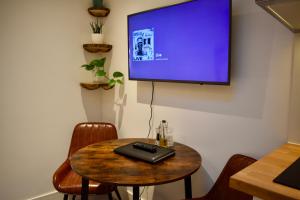 a room with a table with a television on a wall at Stylish centrally-located studio with parking in Croydon