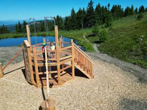 a playground with a wooden deck next to a river at Almhüttendorf Klippitztörl in Klippitztorl