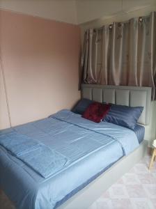 uma cama com lençóis azuis e uma almofada vermelha em JATUPORN A3 em Ban Talat Rangsit