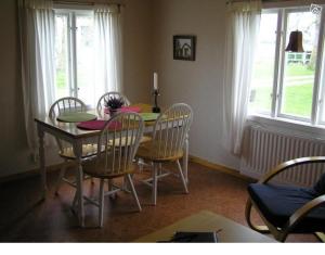 a dining room with a table and chairs and a table and windows at Sydöstra Gotland in Hemse