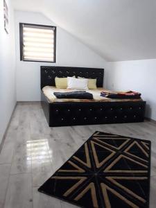 a bedroom with a black bed with a window and a rug at Casa PICY Vendégház in Sovata