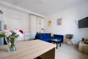 een woonkamer met een blauwe bank en een vaas met bloemen bij Restful Stay Apartment in Grudziądz