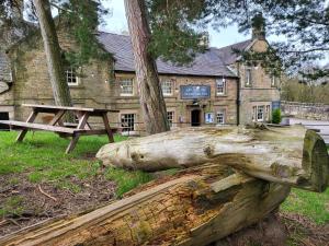 a log and a picnic table in front of a building at The Manifold Inn Hotel in Hartington