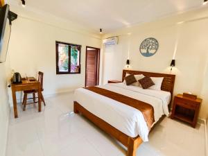 a bedroom with a large bed and a desk at The Tunjung Boutique Resort in Dalung