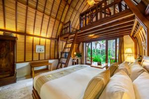 サヌールにあるKlumpu Bali Resortの木製の天井の客室で、ベッドルーム1室(大型ベッド1台付)