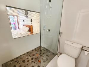 a bathroom with a toilet and a glass shower at The Tunjung Boutique Resort in Dalung