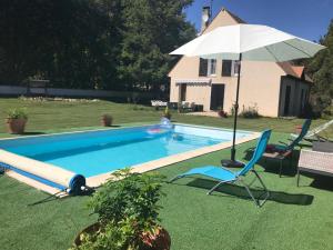 a pool with a umbrella and two chairs at o tour de l'eau in Aubevoye