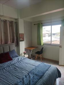 um quarto com uma cama, uma secretária e uma janela em JATUPORN A3 em Ban Talat Rangsit