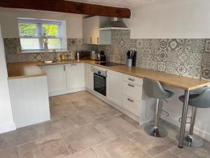 cocina con armarios blancos y encimera de madera en Snowdonia Holiday Cottages, en Conwy