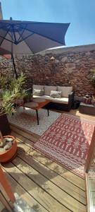 a patio with a couch and an umbrella and a rug at Coquette maison de village in Néfiach