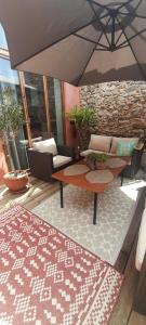 a patio with a couch and a table with an umbrella at Coquette maison de village in Néfiach