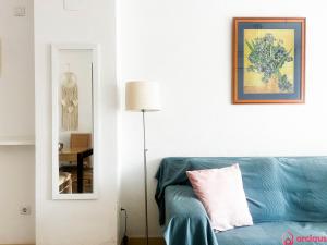 een woonkamer met een blauwe bank en een spiegel bij Como pez en el agua in Oropesa del Mar