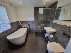 ein Badezimmer mit einer Badewanne, einem WC und einem Waschbecken in der Unterkunft The Manifold Inn Hotel in Hartington