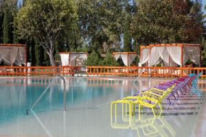 basen z żółtymi krzesłami i stołami oraz basen z wodą w obiekcie Sheraton Istanbul Atakoy Hotel w Stambule