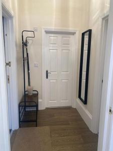 een hal met een witte deur en een spiegel bij Beautiful ground floor flat in Londen