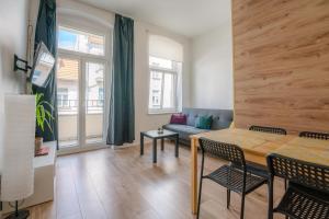 een woonkamer met een tafel en een bank bij Cosy Balcony Apartment in Grudziądz