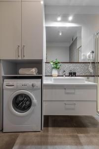 a white kitchen with a washing machine and a sink at Apartament 24 AbsyntApart Rynek Wrocław in Wrocław