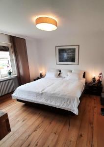 a bedroom with a large white bed with wooden floors at Unter der Linde 1 in Bad Salzuflen
