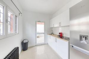 eine weiße Küche mit weißen Schränken und einem Fenster in der Unterkunft Cosy house in La Courneuve