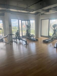 a gym with several tread machines in a room with windows at Two double bedroom duplex flat in London