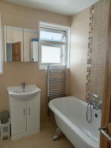 ein Badezimmer mit einer Badewanne, einem Waschbecken und einem Spiegel in der Unterkunft Ocean City Apartment-with parking in Plymouth