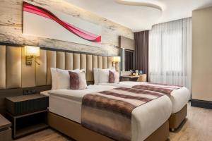 a hotel room with a bed and a painting on the wall at Ramada by Wyndham Istanbul Umraniye in Istanbul