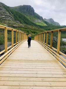 un joven caminando a través de un puente de madera en City Svolvær en Svolvær