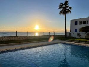 a swimming pool next to a beach with the sunset at Mojácar Vibes 1 Línea de Playa in Mojácar