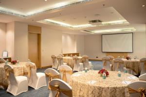 a conference room with tables and chairs and a screen at Sheraton Hyderabad Hotel in Hyderabad